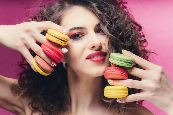 Beauty fashion model girl with colourful manicure taking colorful macaroons