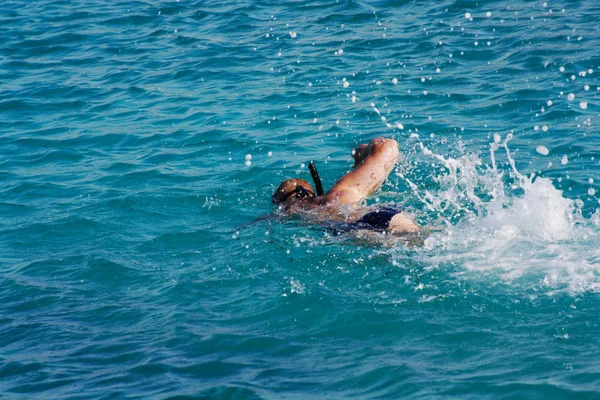 Adam şnorkel ile mavi denizde yüzüyor