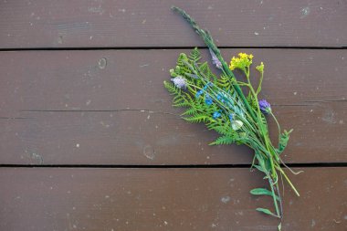 Kır çiçekleri buketi ahşap zemin üzerinde yatıyor.