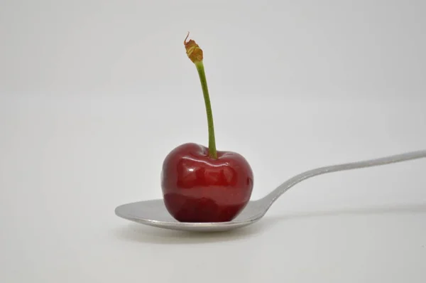 Red cherry on metal spoon