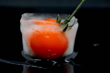 Siyah arka planda donmuş kırmızı domates sebzesi.