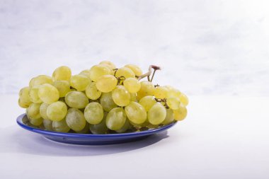 Plaka beyaz zemin üzerine tatlı sarı üzüm dolu
