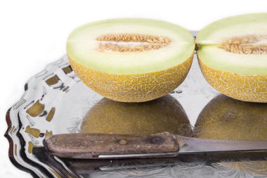 Sarı kavun veya kavun bıçak ile beyaz zemin üzerine eski tepsi üzerinde ayrıntılı olarak ikiye böldüm