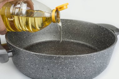 Plastik şişedeki sebze yağı tavaya dökülüyor.
