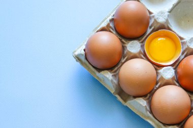 Tavuk yumurtası diğer yumurtaların yanında yarısı kırıktır. Kahverengi yumurta ve yumurta sarısı.