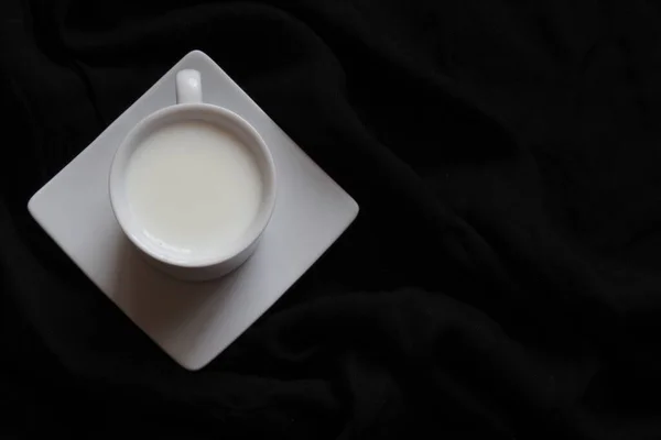 Ev yapımı kompozisyon. Siyah arka planda bir fincan süt. Arka planda kal. Düz konum, üst görünüm, kopyalama alanı — Stok fotoğraf