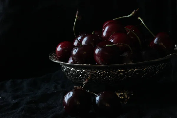 Cerejas maduras doces frescas em prato rústico no fundo preto. Fechar. — Fotografia de Stock