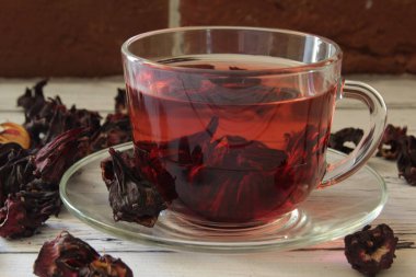 Ahşap bir arka planda cam bir fincanda kırmızı sıcak amber çayı.