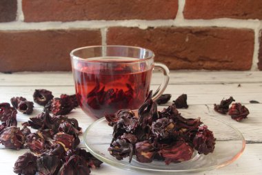 Ahşap bir arka planda cam bir fincanda kırmızı sıcak amber çayı.