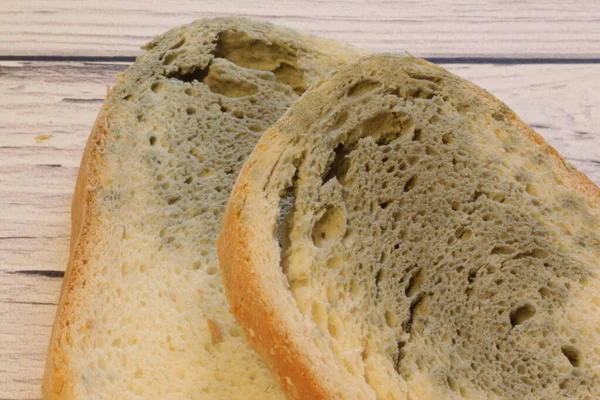 Muffa che cresce rapidamente su pane ammuffito su sfondo di legno. Muffa su una fetta di pane. Pane raffermo, ricoperto di muffa. — Foto Stock