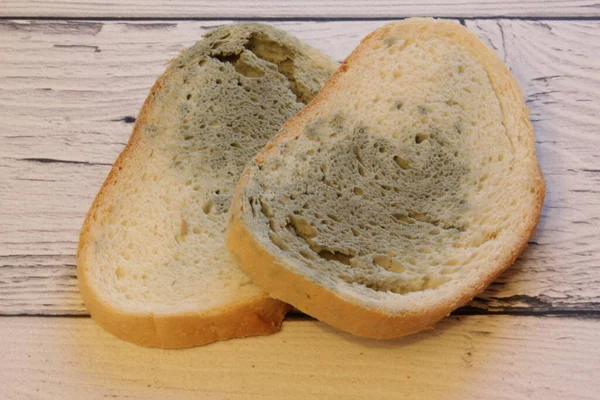 Schimmel groeit snel op beschimmeld brood op houten ondergrond. Meel op een sneetje brood. muf brood, bedekt met meeldauw. — Stockfoto