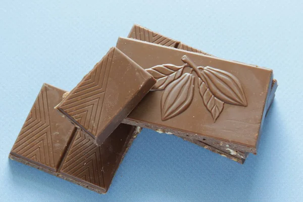 Melk chocolade stukken geïsoleerd op blauwe achtergrond van bovenaf bekijken. Close up een chocolade bar geïsoleerd op blauwe achtergrond. — Stockfoto