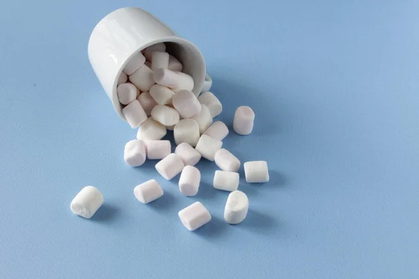 Weiße flauschige Marshmallows in weißer Tasse isoliert auf blauem Hintergrund. Mini-Marshmallows. Hintergrundkonzept Winternahrung. — Stockfoto