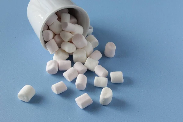 Weiße flauschige Marshmallows in weißer Tasse isoliert auf blauem Hintergrund. Mini-Marshmallows. Hintergrundkonzept Winternahrung. — Stockfoto