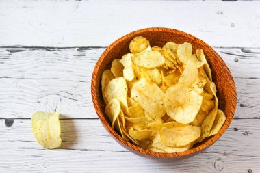 Beyaz ahşap arka planda patates cipsi ya da ahşap kasede cips. Bir yığın patates cipsi. Patates cipsi aperatiftir. Üst görünüm