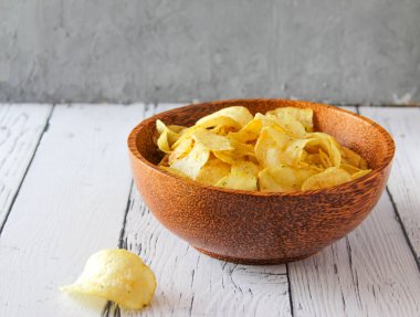 Beyaz ahşap arka planda patates cipsi ya da ahşap kasede cips. Bir yığın patates cipsi. Patates cipsi aperatiftir. Üst görünüm