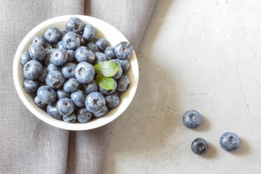 Beyaz kasede taze yaban mersini. Yeşil yapraklı taze yaban mersini. Sağlıklı beslenme ve beslenme kavramı. Üst Manzara. Boşluğu kopyala.