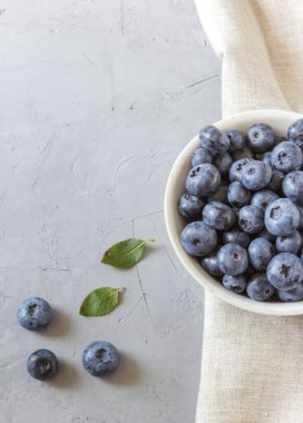 Beyaz kasede taze yaban mersini. Yeşil yapraklı taze yaban mersini. Sağlıklı beslenme ve beslenme kavramı. Üst Manzara. Boşluğu kopyala.