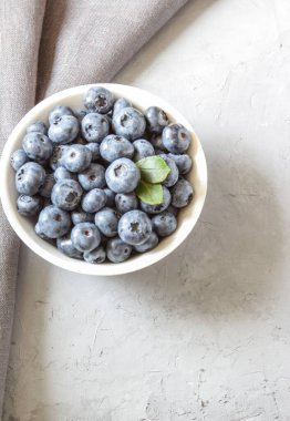 Beyaz kasede taze yaban mersini. Yeşil yapraklı taze yaban mersini. Sağlıklı beslenme ve beslenme kavramı. Üst Manzara. Boşluğu kopyala.