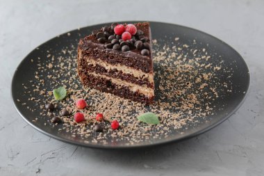 Siyah bir tabakta nane yapraklı ve meyveli çikolatalı kek.