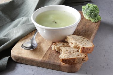 Brokoli çorbası beyaz tabakta, ahşap zemin üzerinde.