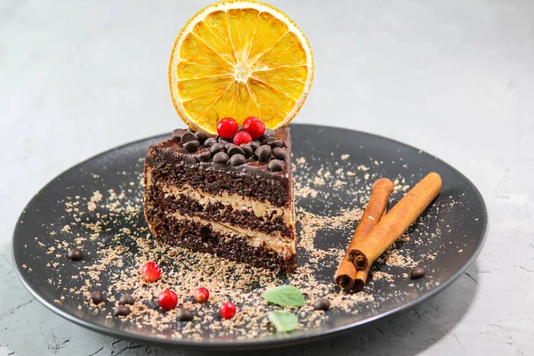 Siyah bir tabakta nane yapraklı ve meyveli çikolatalı kek.