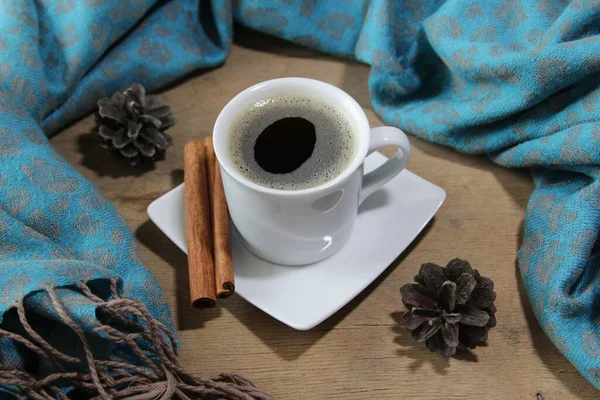 Autunno o inverno composizione accogliente. Tazza di caffè, plaid a maglia calda, bastoncini di cannella e pigne su fondo di legno. — Foto Stock