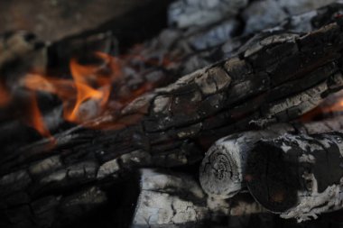 Yanmış odunlar yakın çekim ateşinde yanmış. Atmosferik arka plan ve kamp ateşi. İçeriden kopyalanmış şenlik ateşinin tasavvur edilemez detaylı görüntüsü. Duman fırtınası ve parlayan közler..