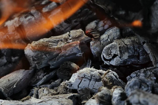 Smoldered logs burned in vivid fire close up. Atmospheric background with flame of campfire. Unimaginable detailed image of bonfire from inside with copy space. Whirlwind of smoke and glowing embers. — Stock Photo, Image
