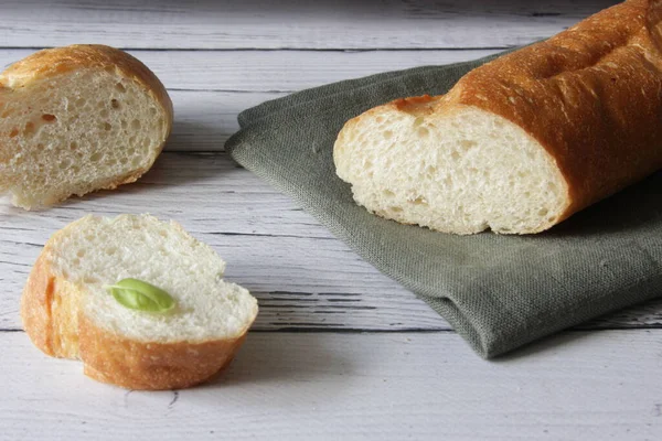 Französisch frisches Baguette auf Serviette und hölzernem Hintergrund. Mehrere zerschnittene Stücke liegen nebeneinander. — Stockfoto