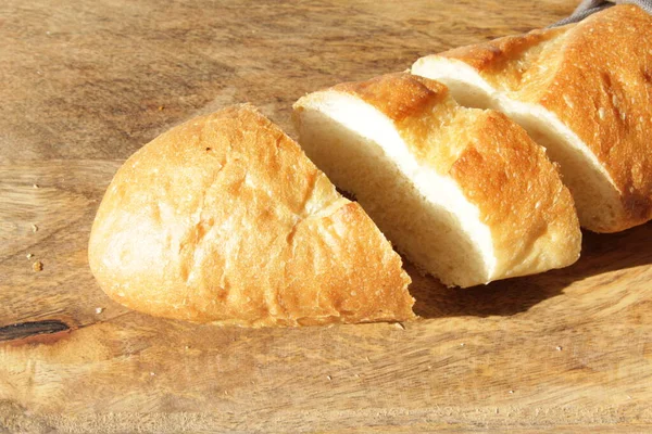 Französisches frisches Baguette auf einem hölzernen Schneidebrett. Mehrere zerschnittene Stücke liegen nebeneinander. — Stockfoto