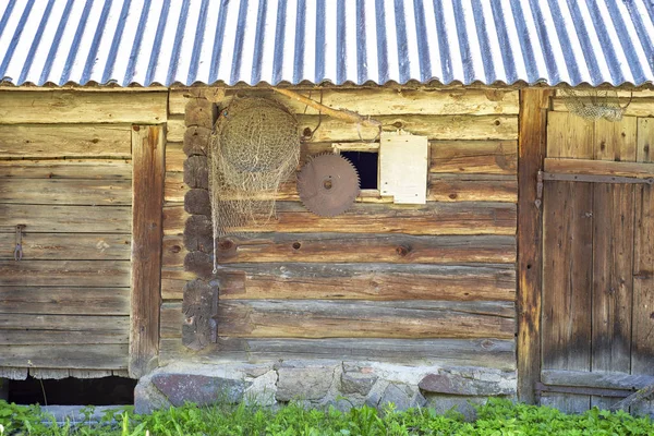 Antigua casa de madera grunge, red y sierra colgando en la pared —  Fotos de Stock
