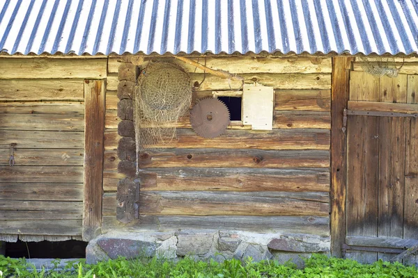 Old grunge wooden house, net and saw hanging on the wall — Stock Photo, Image