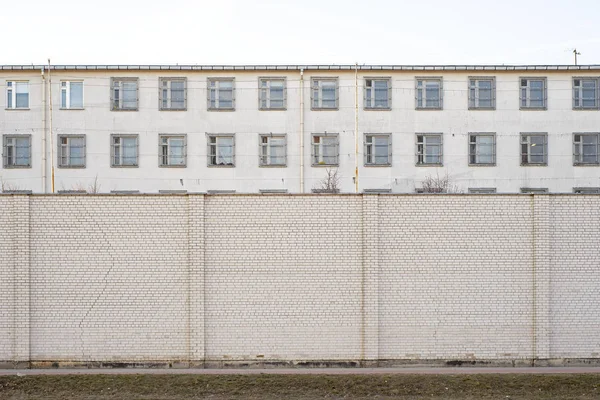 버려진된 건물 큰 흰색 벽돌 벽으로 둘러싸인. — 스톡 사진