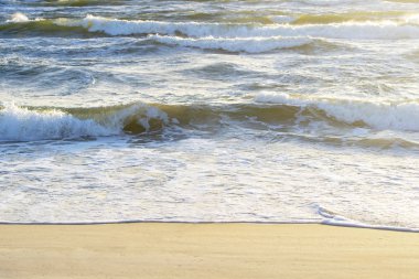 Dalgalı Denizi ve yaz aylarında kumlu deniz kıyısı.