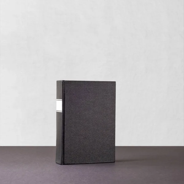 Czarna Księga z białą ramkę na kręgosłup stojący na ciemnej powierzchni — Zdjęcie stockowe