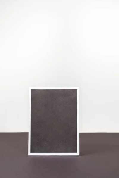 Marco negro en blanco de la imagen de pie sobre la mesa negra . — Foto de Stock