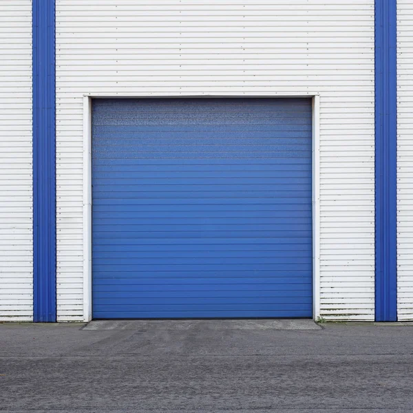 White Industrial warehouse with blue door for trucks. — Stock Photo, Image