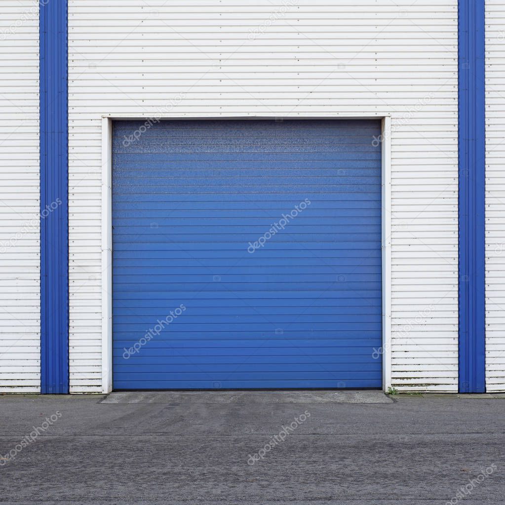 White Industrial warehouse with blue door for trucks.