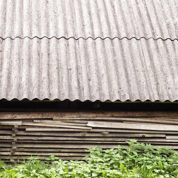Tábuas de madeira velhas empilhadas sob o telhado do galpão velho . — Fotografia de Stock