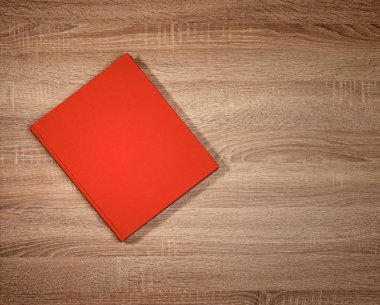 Koyu kahverengi ahşap masa üzerinde kırmızı kitap.