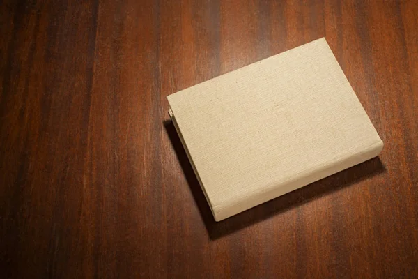 Beige color book on the wooden scratched table. — Stock Photo, Image