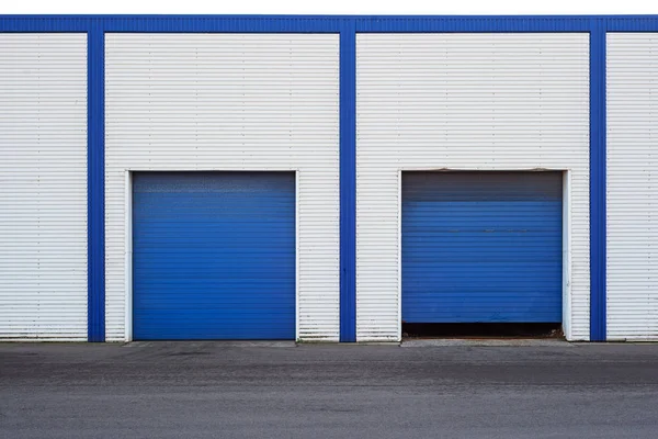 Weißes Industrielager mit blauer Tür für LKW. Stockfoto