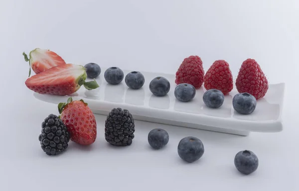 Fresh berries  on a white dish on a white background.  - Imagen