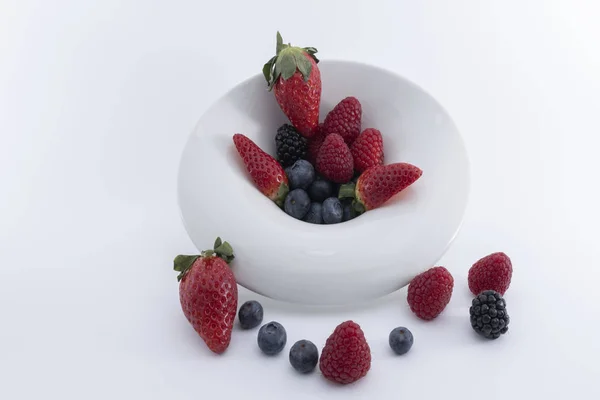 Fresh berries on a white dish on a white background.  - Imagen