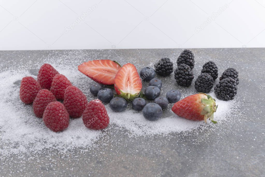 Fresh berries  on a plate of granite whith sugar on a white background.  - Imagen