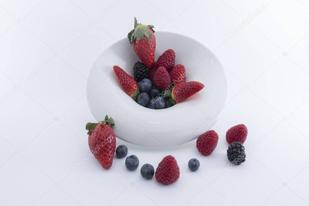 Fresh berries  on a white dish on a white background.  - Imagen