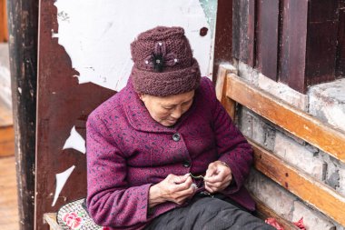 Fenghuang, Hunan, Çin - 12 Aralık 2018: bir tanımlanamayan yaşlı kadınlar oturup bir tezgah ve dikiş Fenghuang sokak
