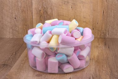 plastik konteyner ahşap arka plan üzerinde renkli hatmi şekerler.