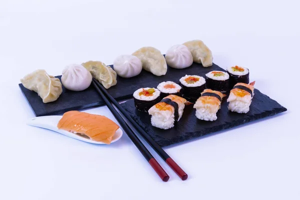 Wonton a sushi se rojí na černé břidlici. — Stock fotografie